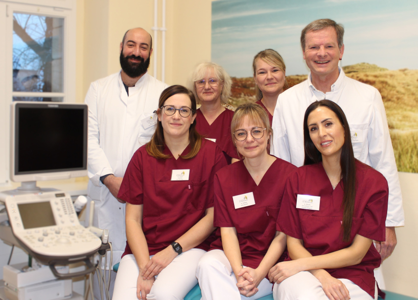 Das Team des Brustzentrums, vier Damen in weinroten Kasaks und links und rechts zwei Herren in weißen Arztkitteln lächeln in die Kamera.