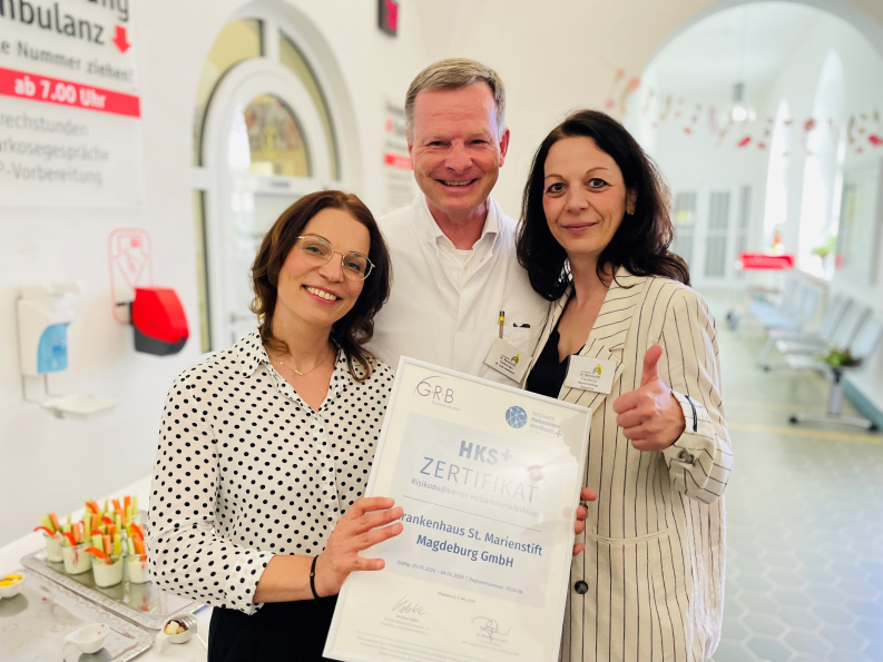Frau Dr. Klammt, Chefarzt Dr. Hartmann und Melanie Hennig lächeln stolz in die Kamera und halten das Zertifikat in ihren Händen. 
