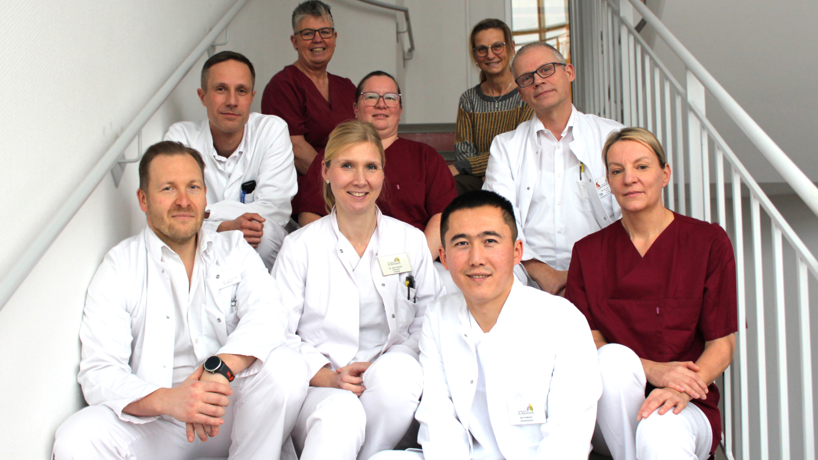 Die Kolleginnen und Kollegen der Klinik für Urologie sitzen auf einer Treppe und lächeln in die Kamera.
